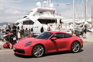 Porsche 911 in Rot steht vor weißer Luxus-Yacht in Saint-Tropez.